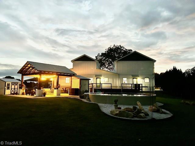 Image 1: Twilight photo of back of home showing pool and pavillion provided by seller.