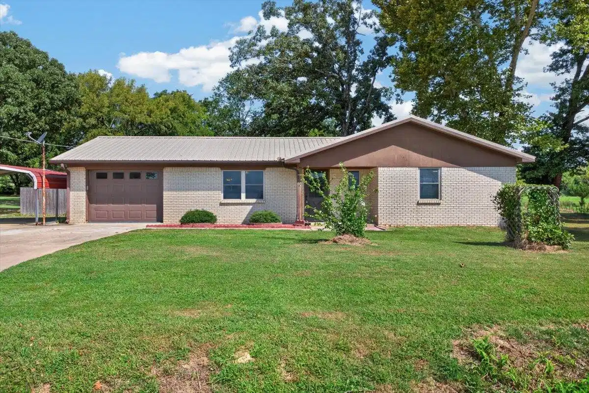 Image 1: Brick exterior with a metal roof, attached garage,