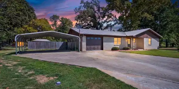 Image 2: Brick exterior with a metal roof, attached garage,