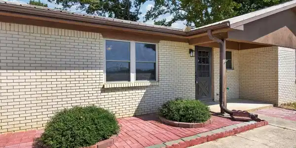Image 4: Light brick exterior with brown trim, covered entr