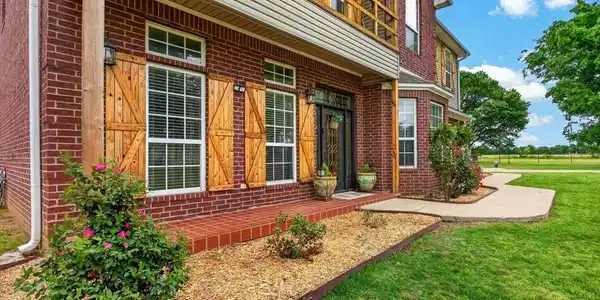 Image 3: Brick exterior featuring a covered porch with a wo