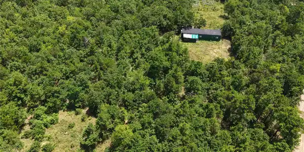 Image 4: Rural acreage featuring extensive tree cover, a si