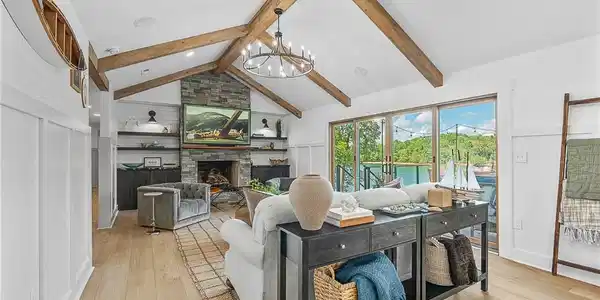 Image 4: Exposed wood beams and a stone fireplace anchor th