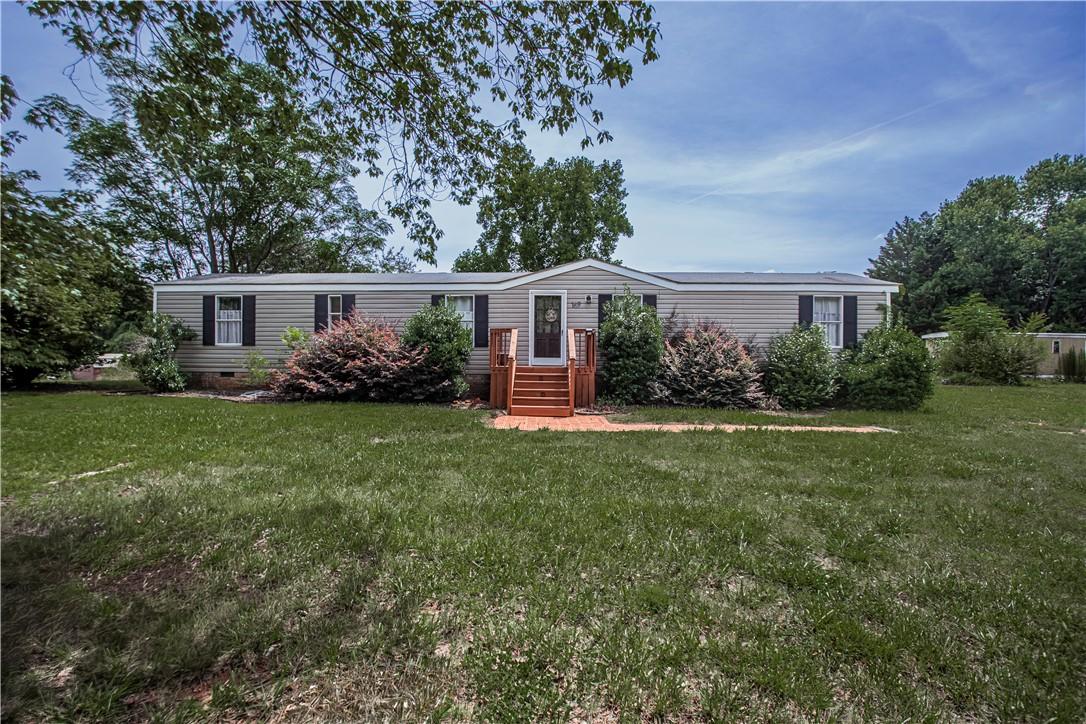 Image 1: Well-maintained manufactured home nestled amidst l