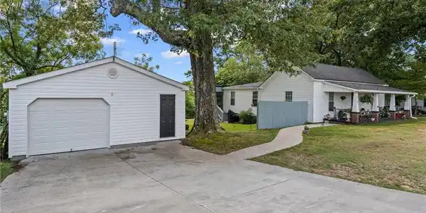 Image 3: Mature trees shade a concrete driveway leading to
