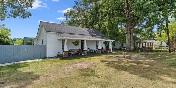 Image 4: Mature shade trees frame a classic covered front p
