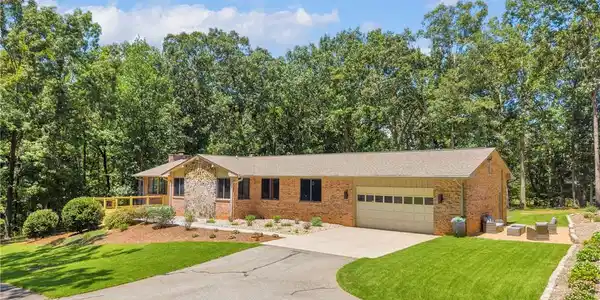 Image 2: A well-maintained brick and stone home with an att