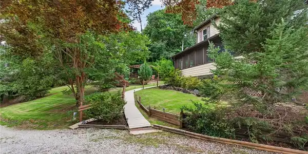 Image 3: A winding pathway leads through lush greenery to a