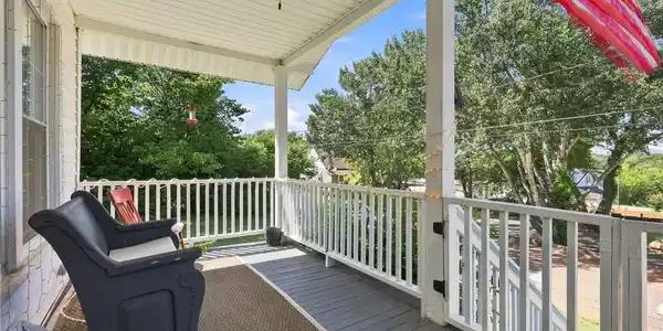 Image 2: An elevated covered porch features painted wood de