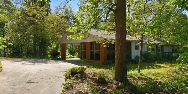 Image 4: This charming home sits amidst a lush, verdant lan