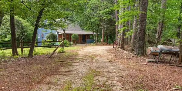Image 2: A secluded wooded driveway leads to a charming rus